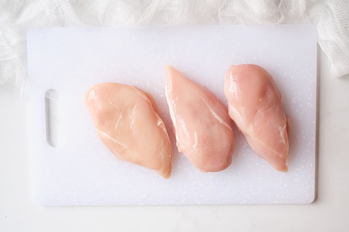 three pieces of chicken tenderloin on a cutting board
