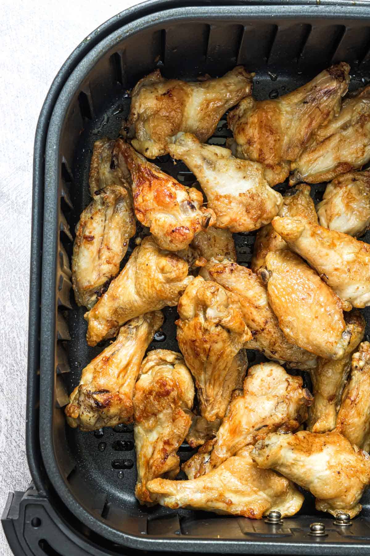 close up view of frozen chicken wings in air fryer basket