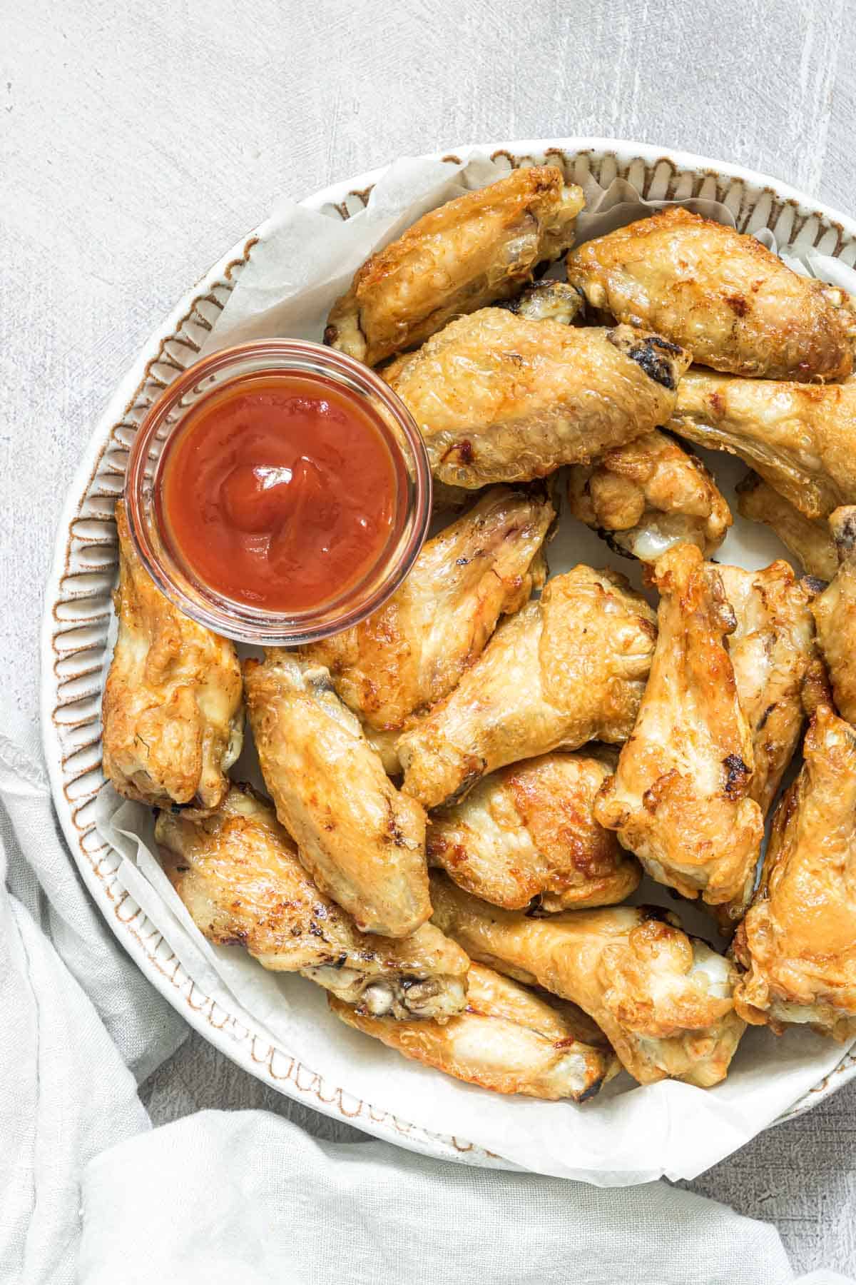 top down view of cooked frozen chicken wings in air fryer served on a plate with dipping sauce