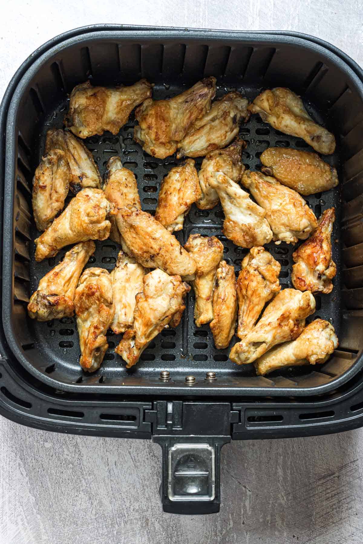 top down view of frozen chicken wings in air fryer basket