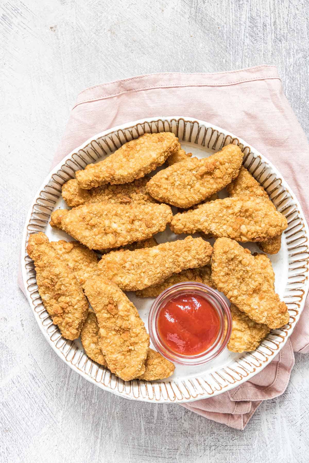 one serving of frozen chicken tenders in air fryer on a white plate with dipping sauce