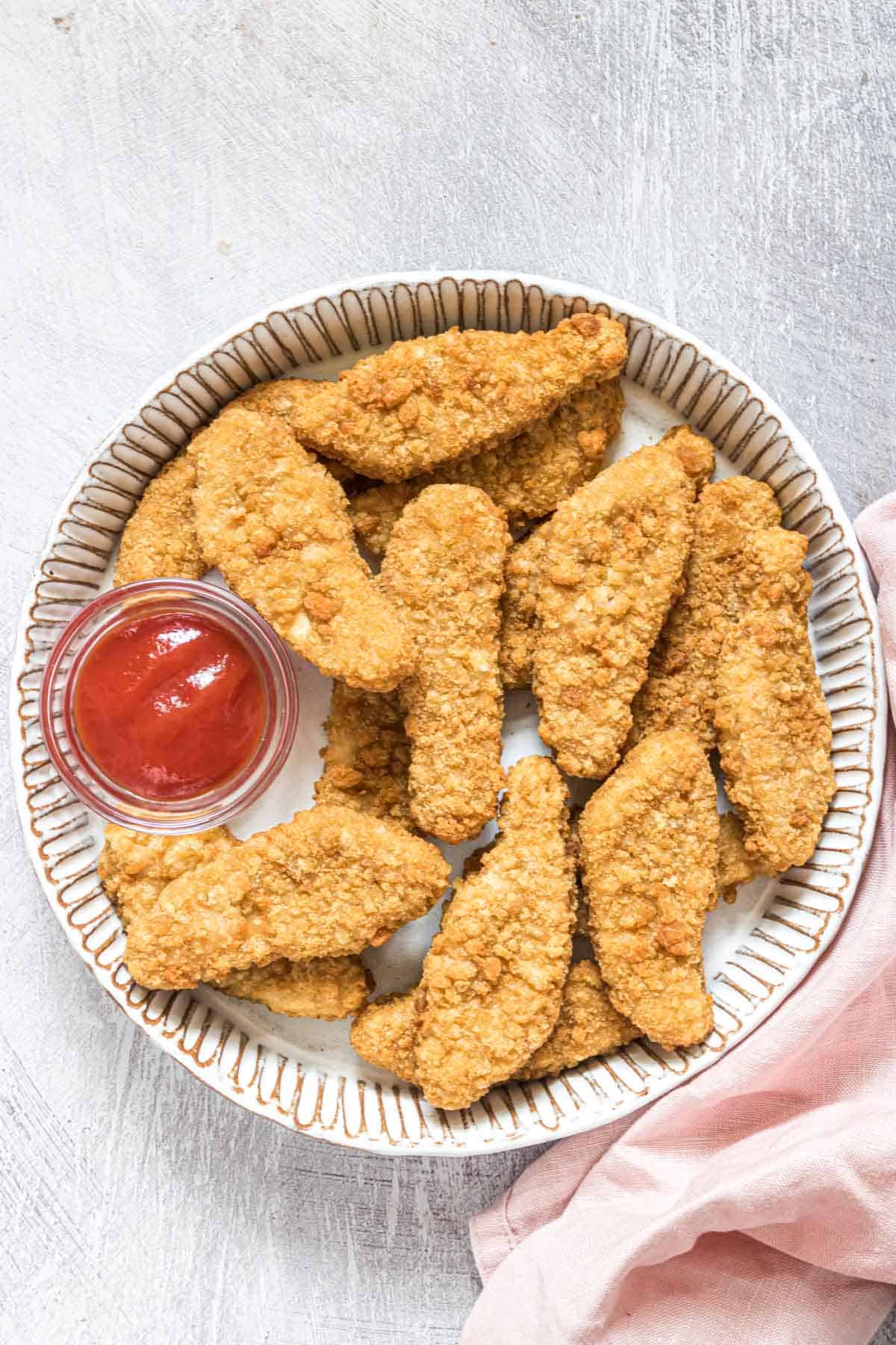 top down view of a plate filled with cooked frozen chicken tenders in air fryer