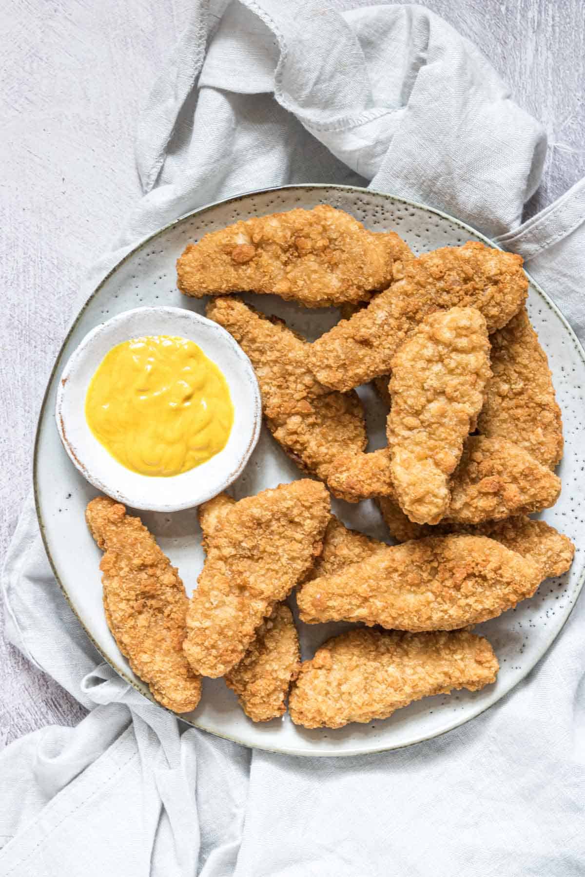 chicken tenders that have been reheated in air fryer and served on a plate with dipping sauce