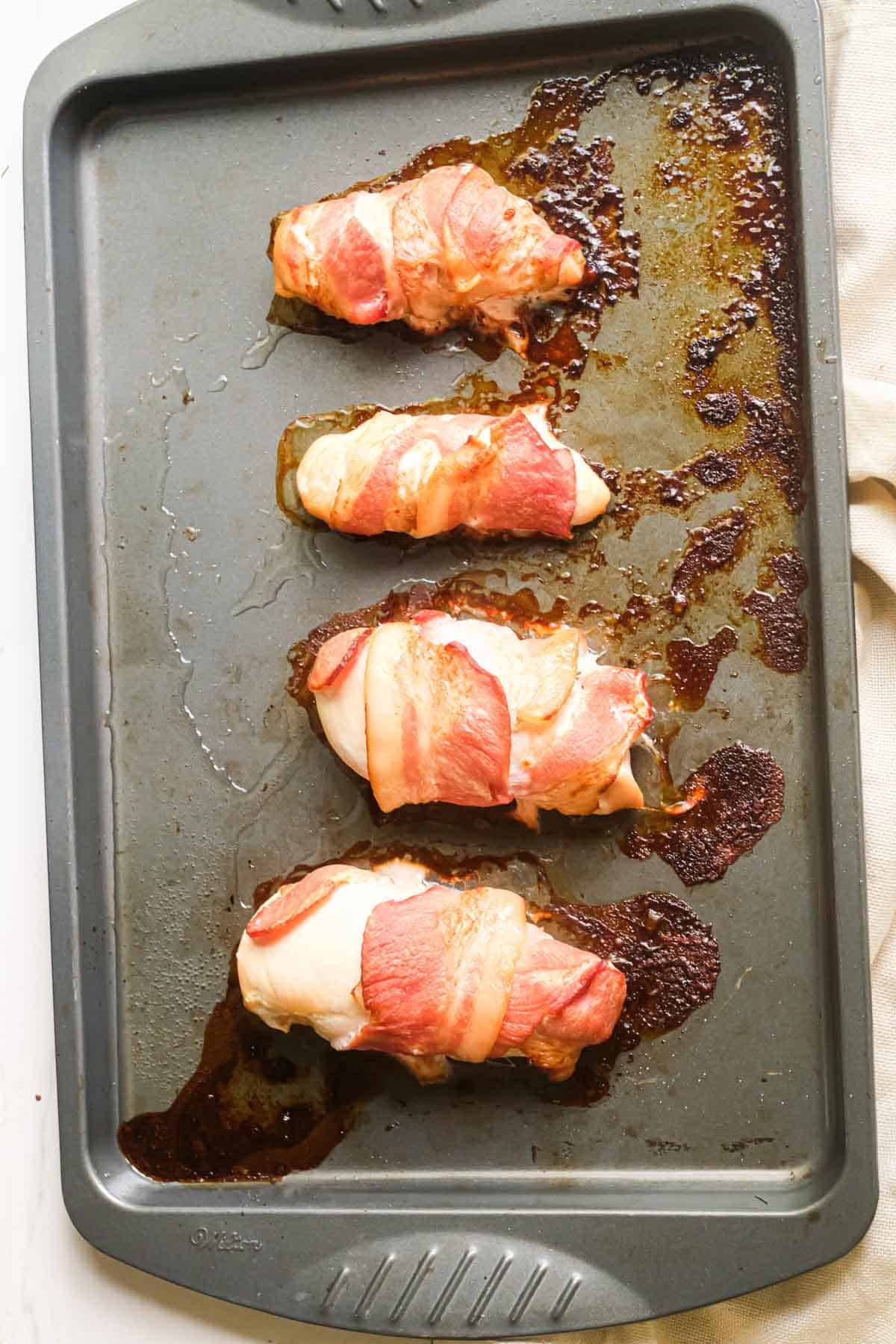 top down view of bacon wrapped chicken breast on a baking sheet