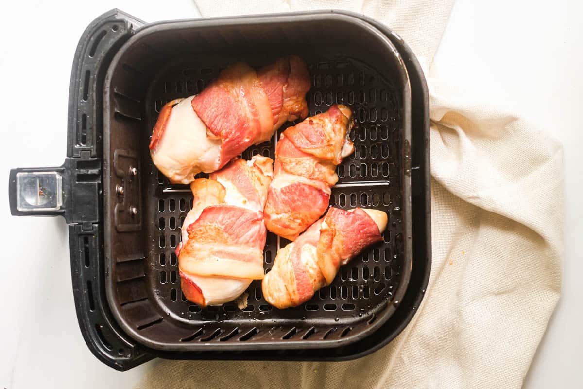 the completed bacon wrapped chicken in air fryer basket