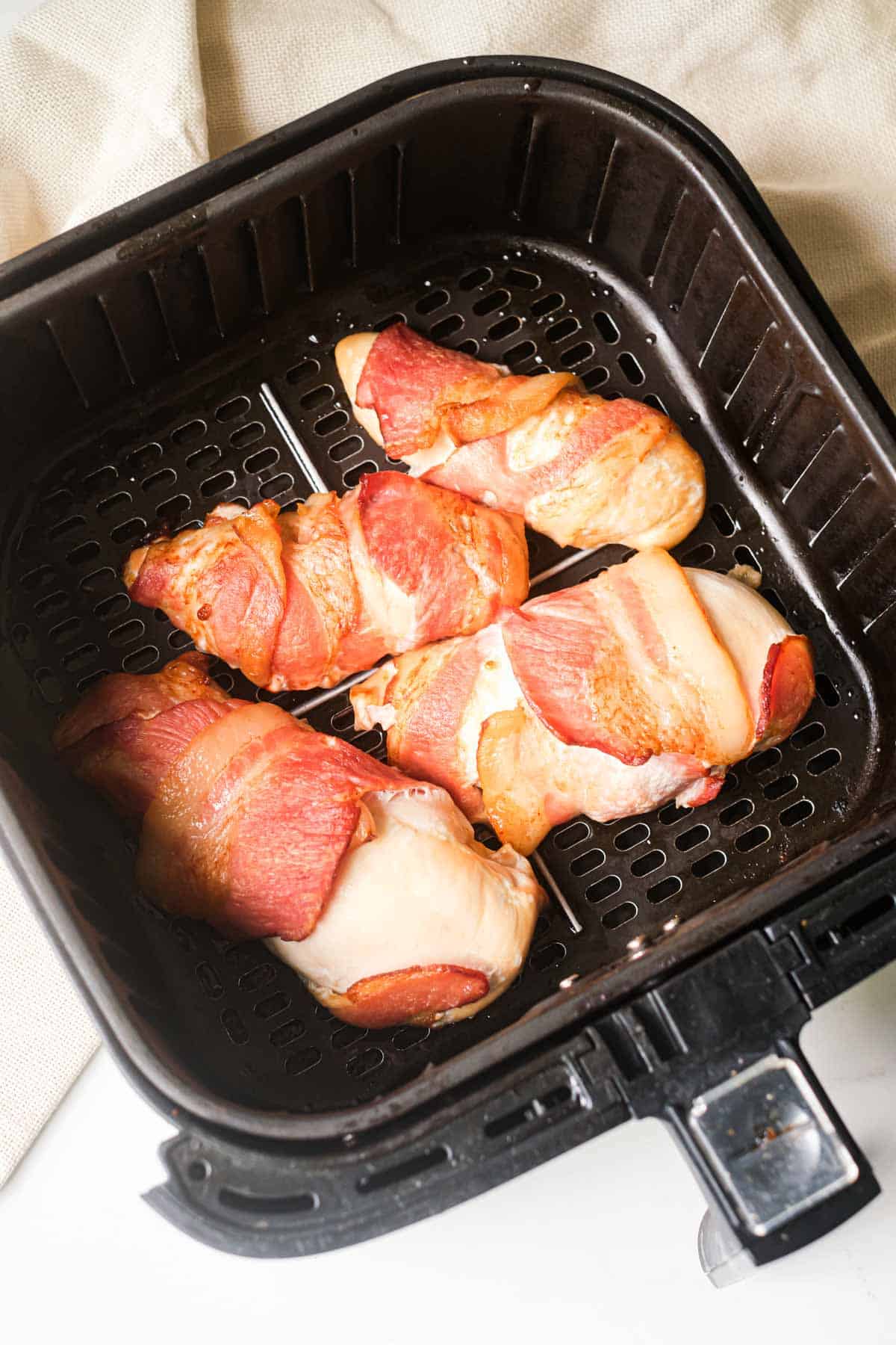 the finished bacon wrapped chicken breast in air fryer basket