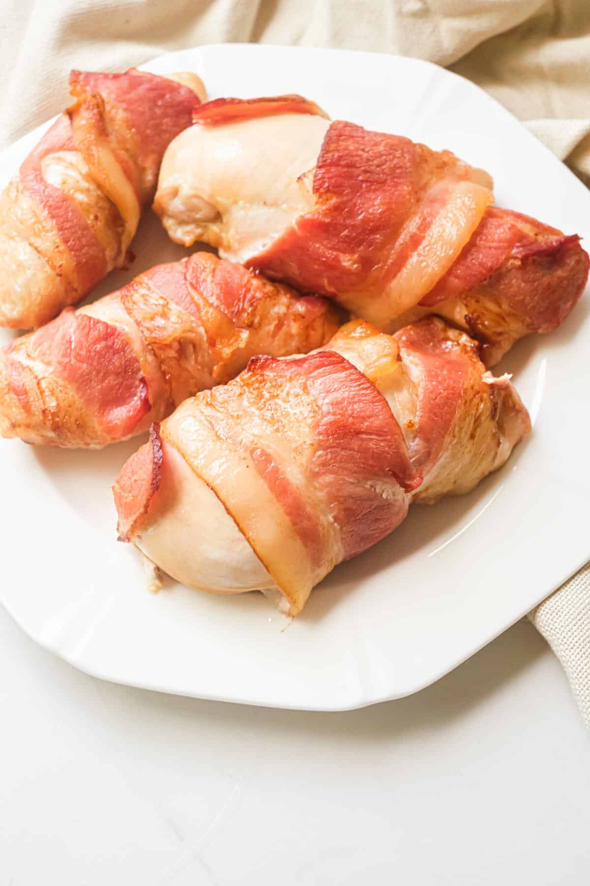 the finished bacon wrapped chicken breast on a white plate