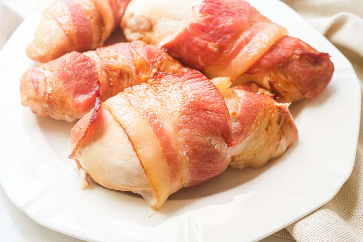 the completed bacon wrapped chicken breast served on a white plate