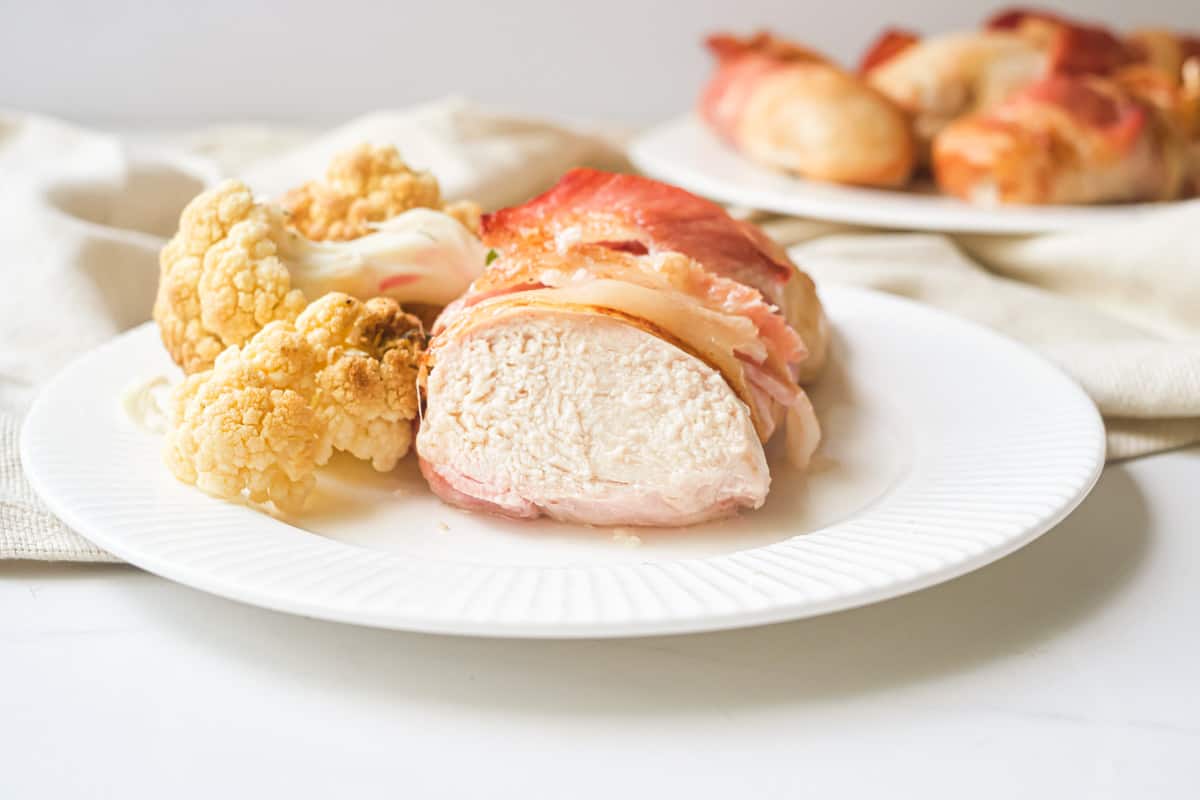 oneair fryer bacon wrapped chicken breast served on a plate with a side of cauliflower