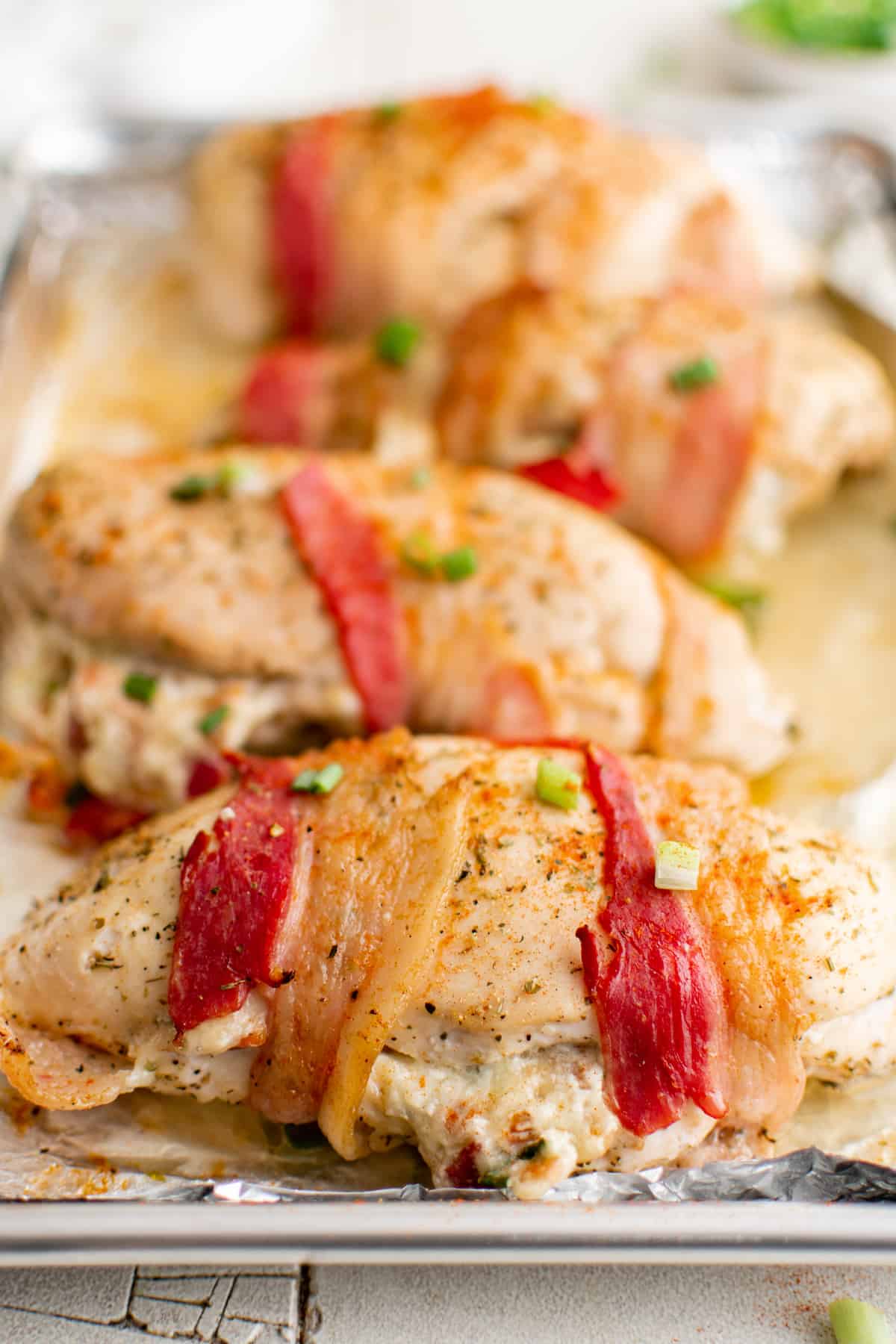 close up view of the completed bacon wrapped stuffed chicken breast on a baking tray