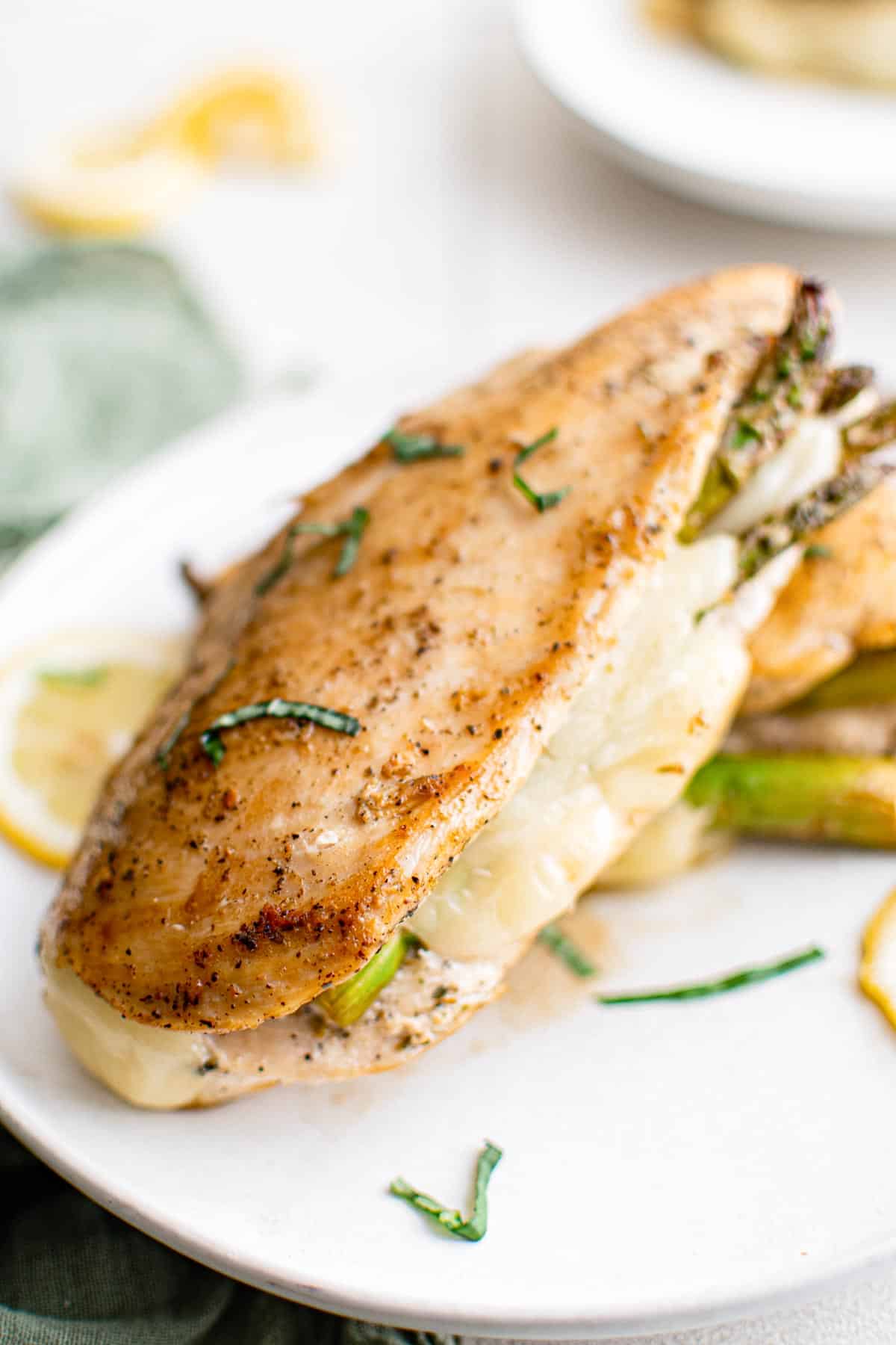 close up of one asparagus stuffed chicken breast served on a white plate