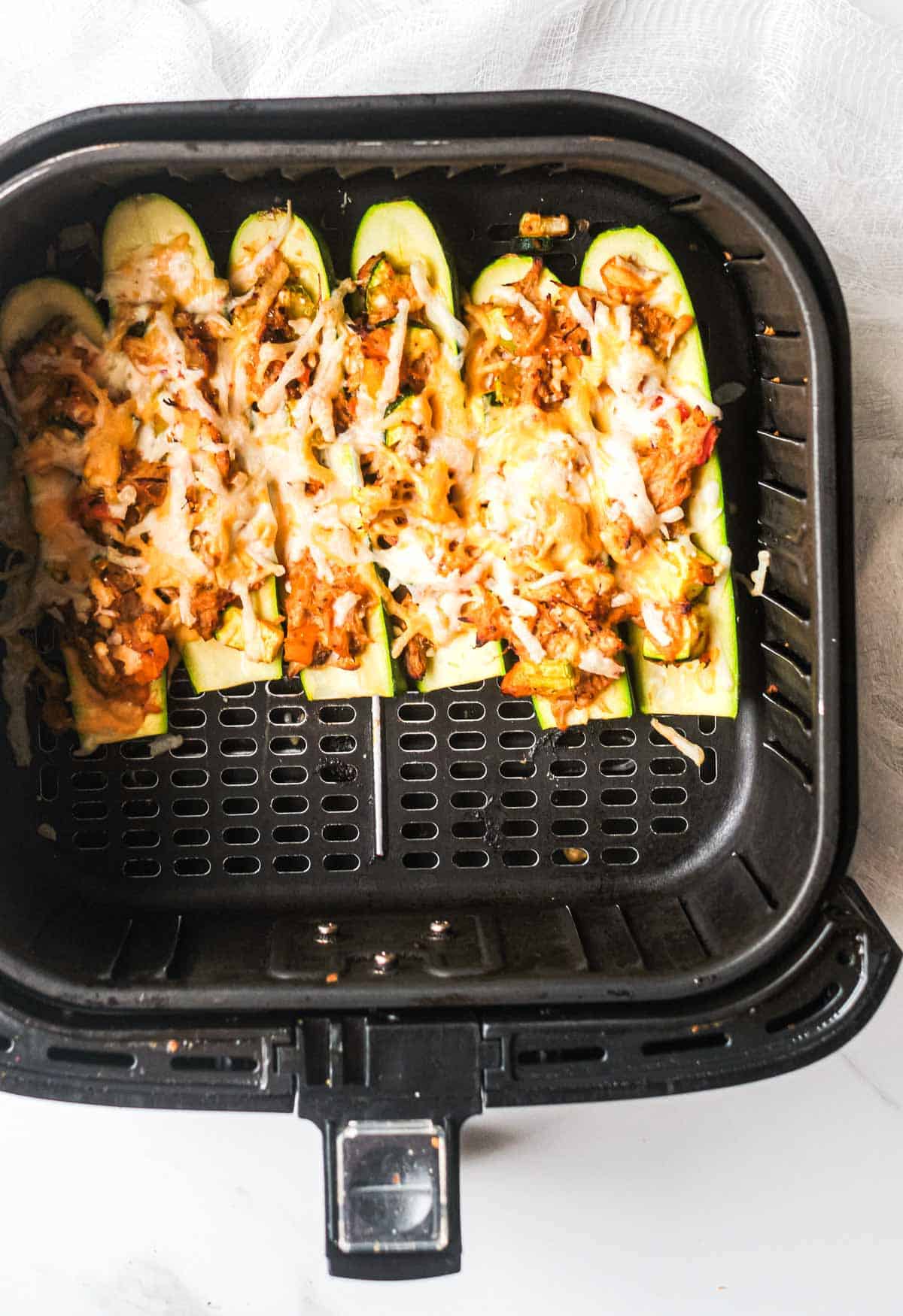 top down view of the cooked buffalo chicken zucchini boats inside the air fryer basket