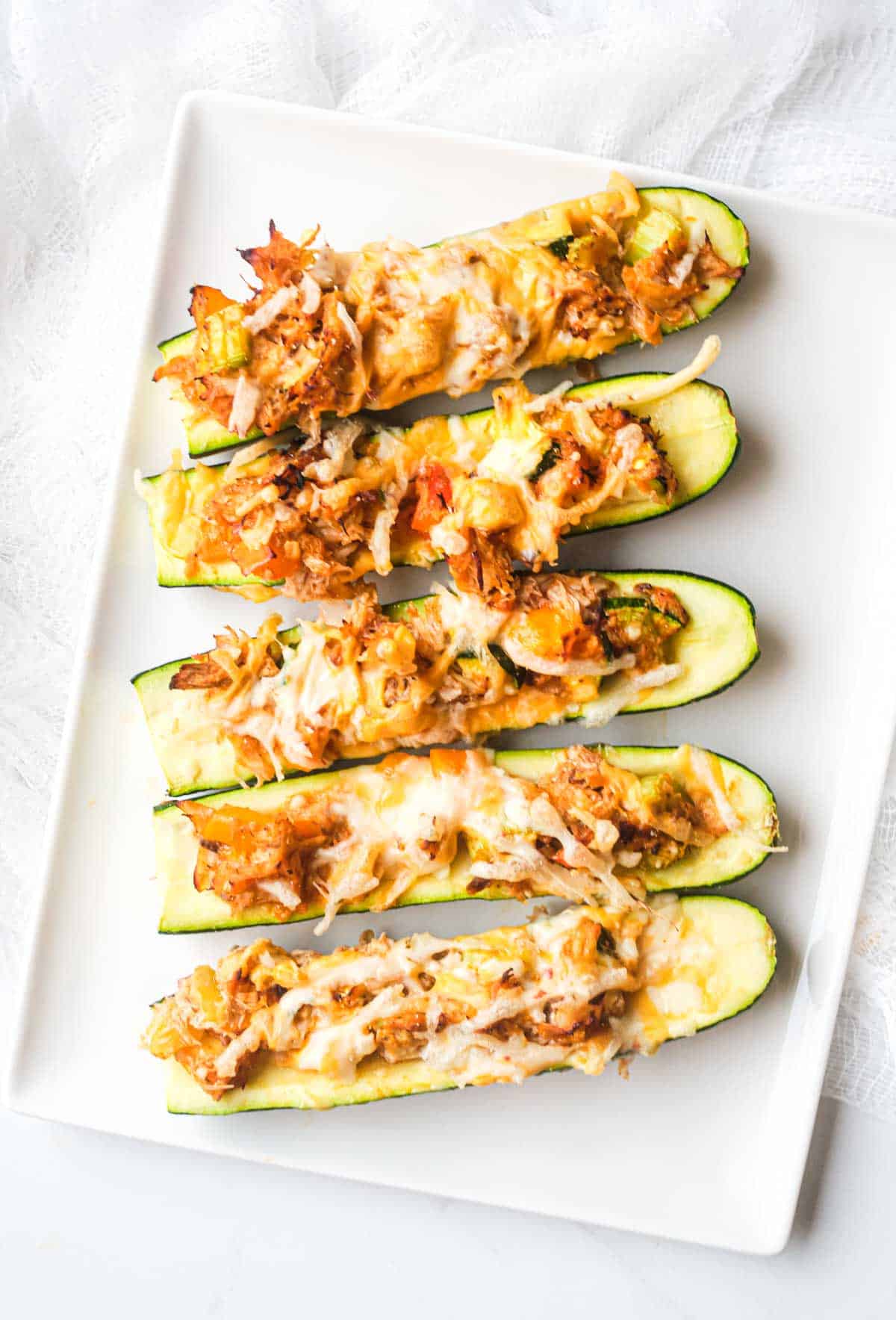top down view of the buffalo chicken zucchini boats on a white platter