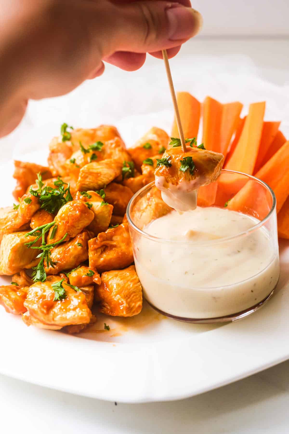 a hand dipping one of the buffalo chicken bites into ranch dressing