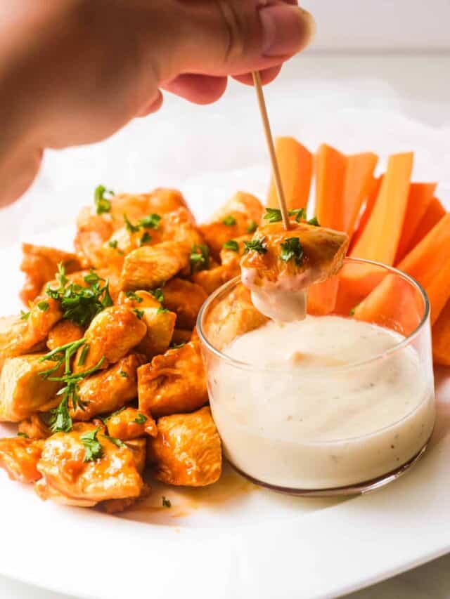 a hand dipping one of the buffalo chicken bites into ranch dressing