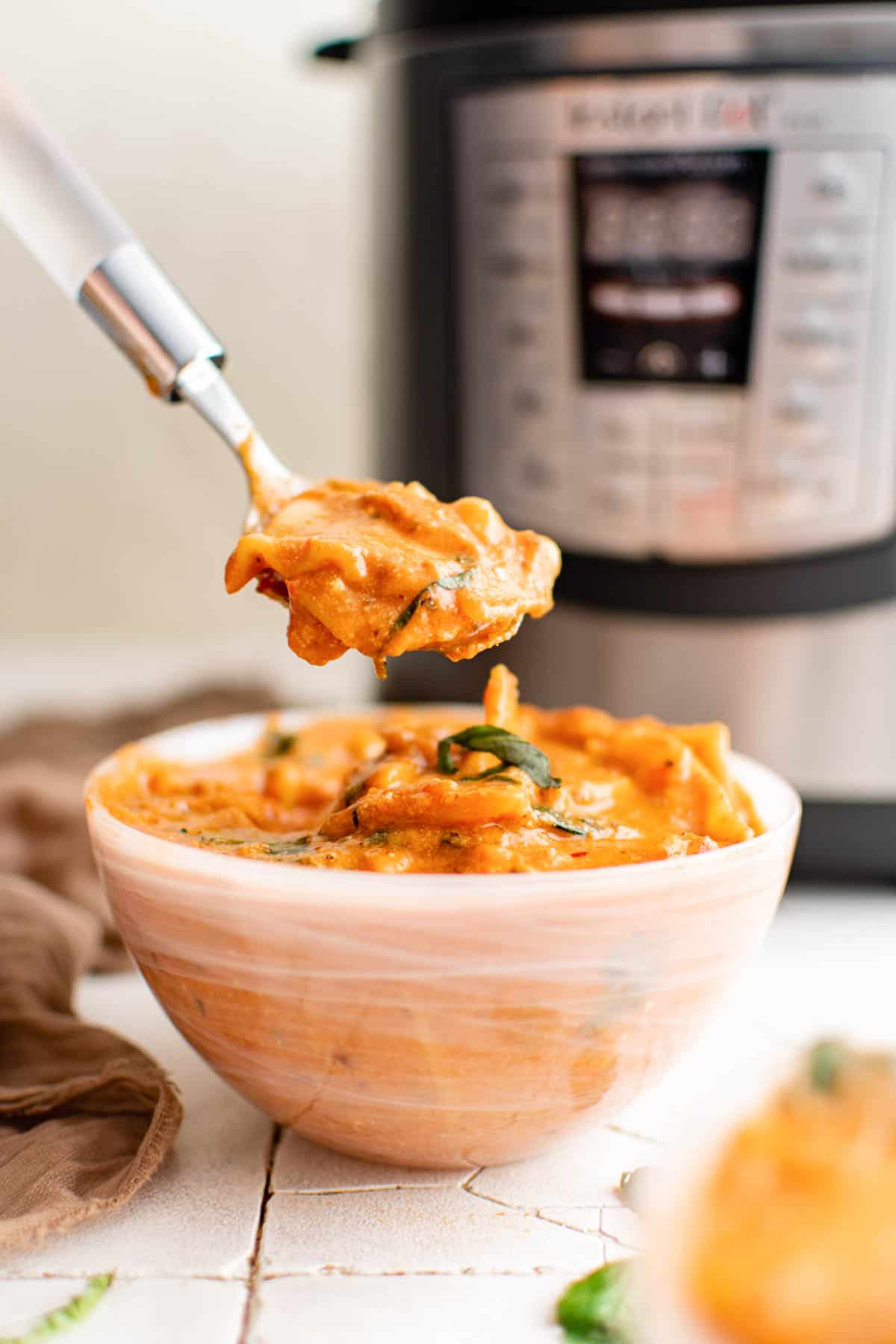 a spoon removing one bite of instant pot lasagna soup from a bowl