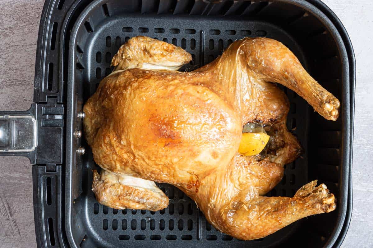 close up view of a whole rotisserie chicken reheat in air fryer basket