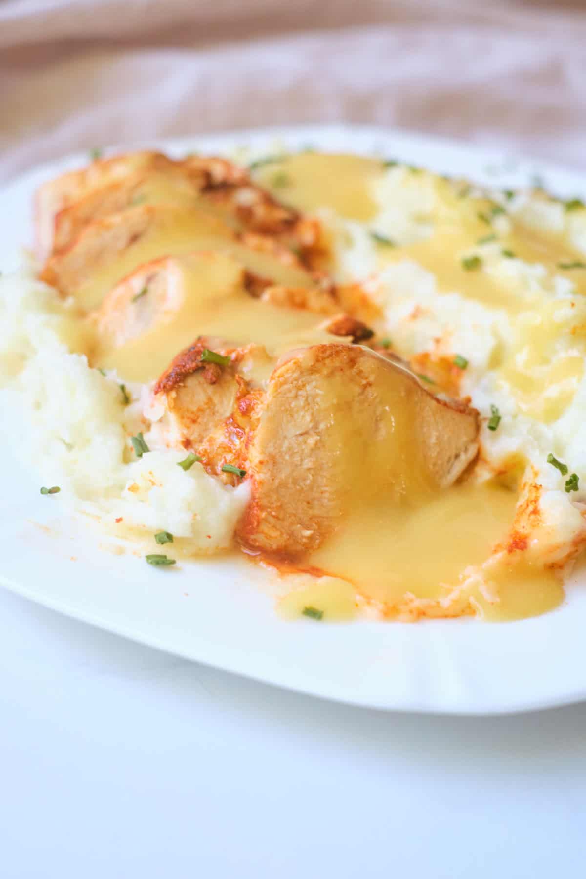 a serving of instant pot chicken breast on top of mashed potatoes and covered with gravy
