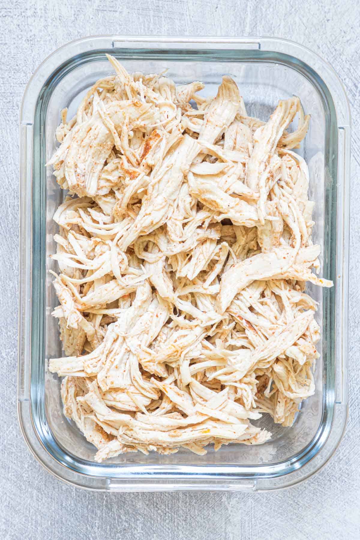 instant pot shredded chicken in a glass meal storage container