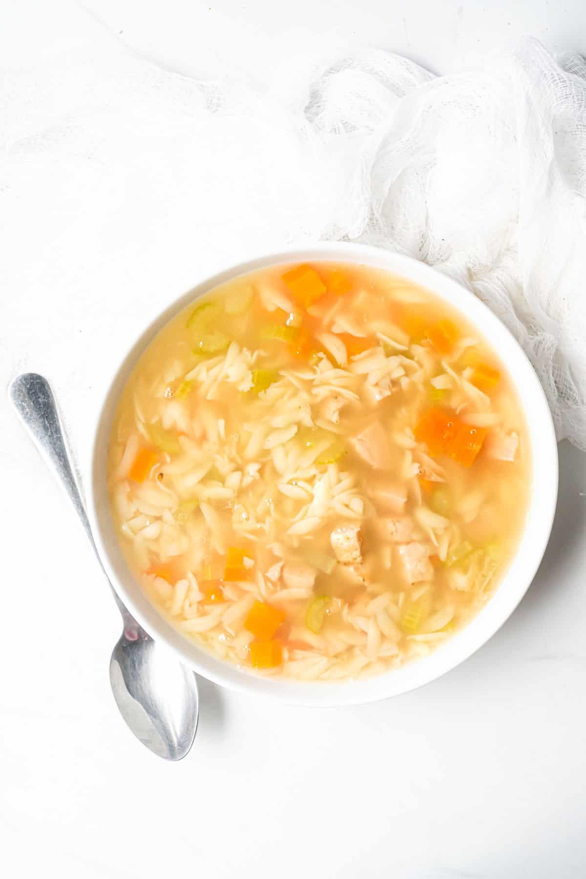 one serving of the completed instant pot lemon chicken orzo soup in a white bowl