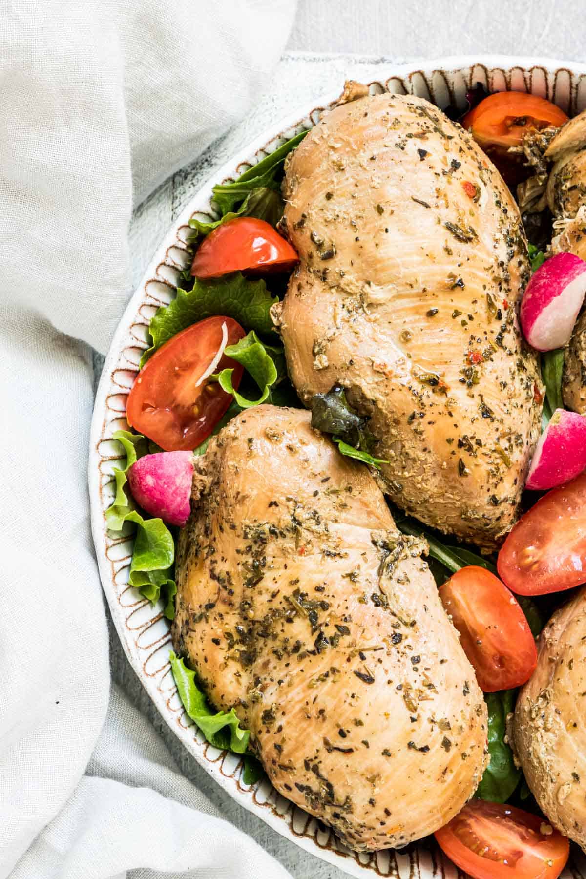 close up view of the finished instant pot frozen chicken breast served with tomatoes and greens.