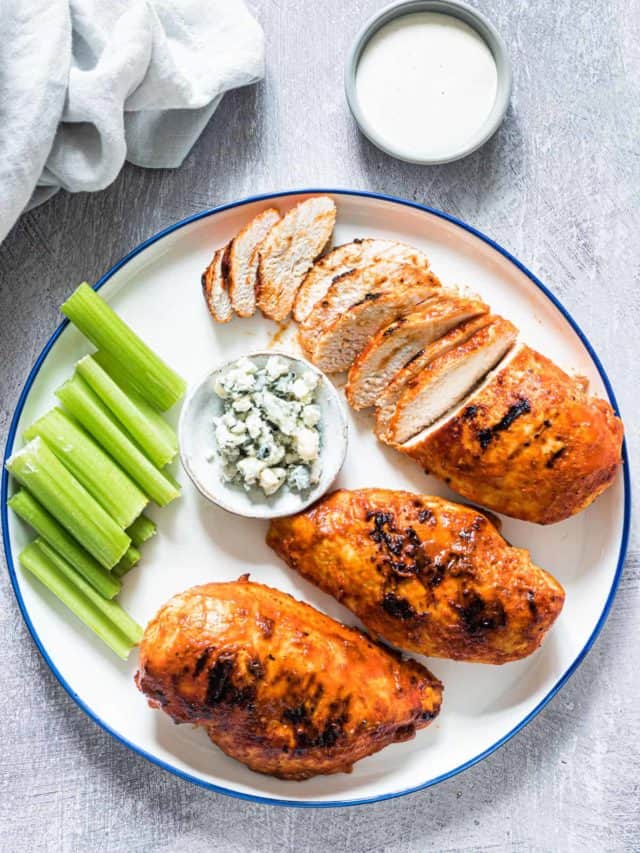 a plate of grilled buffalo chicken breasts with some sliced with garnishes