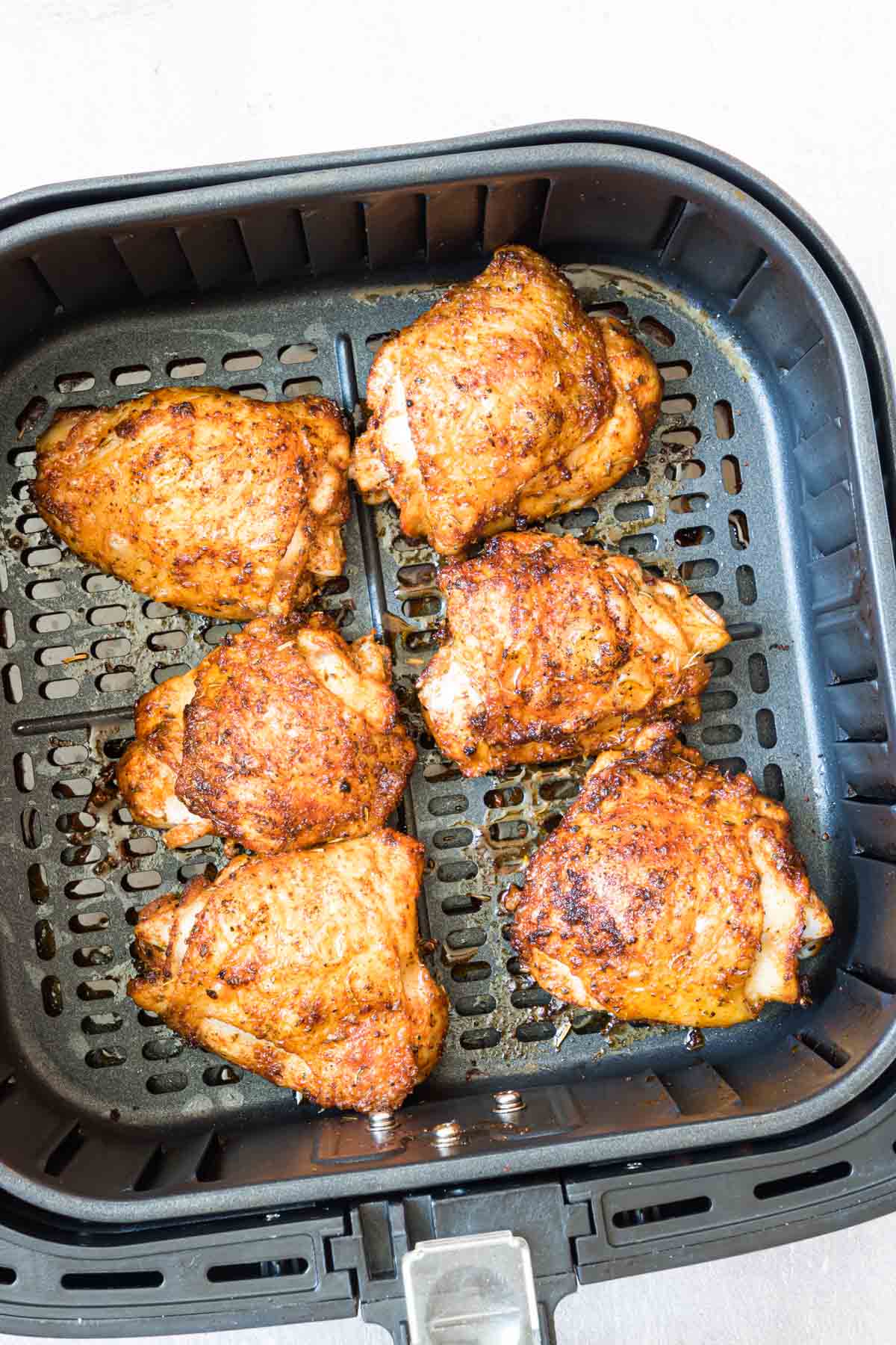 the finished air fryer chicken thighs in the air fryer basket