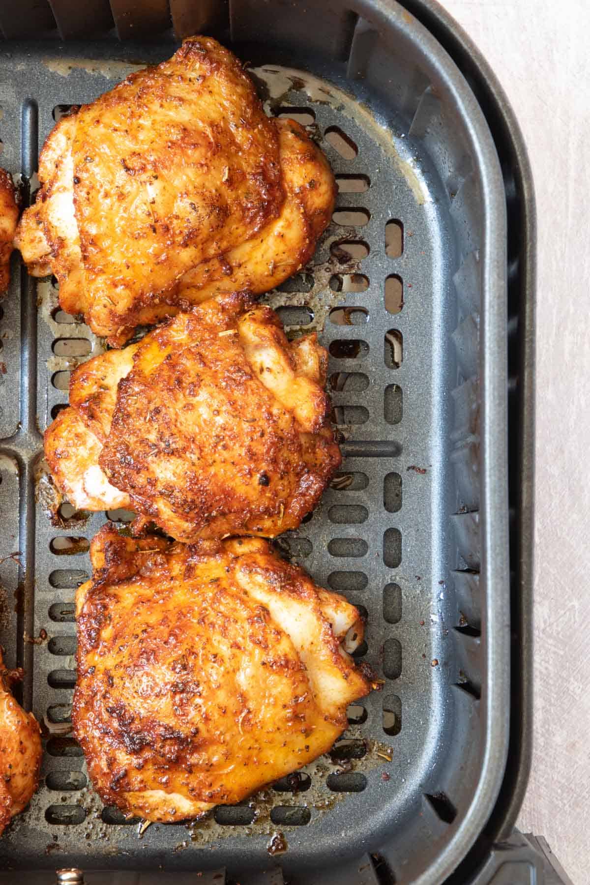 the completed air fryer chicken thighs inside the air fryer basket and ready to serve