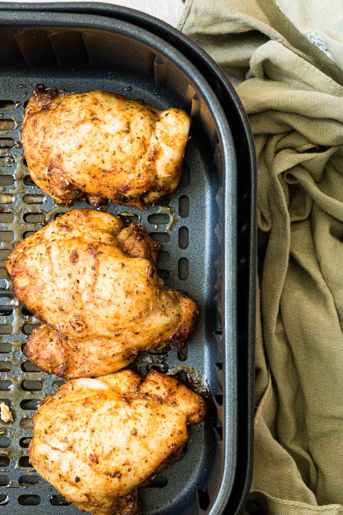 close up view of the air fryer chicken thighs inside the air fryer basket