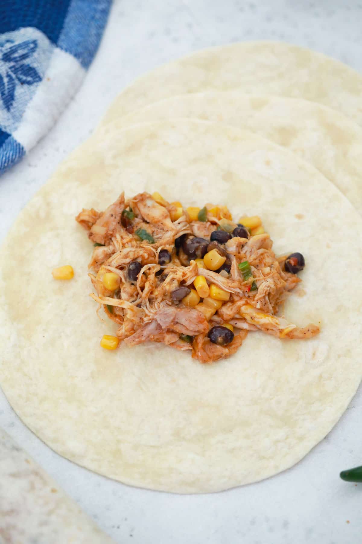 Close up of a tortilla with chicken taquito filling in the middle.