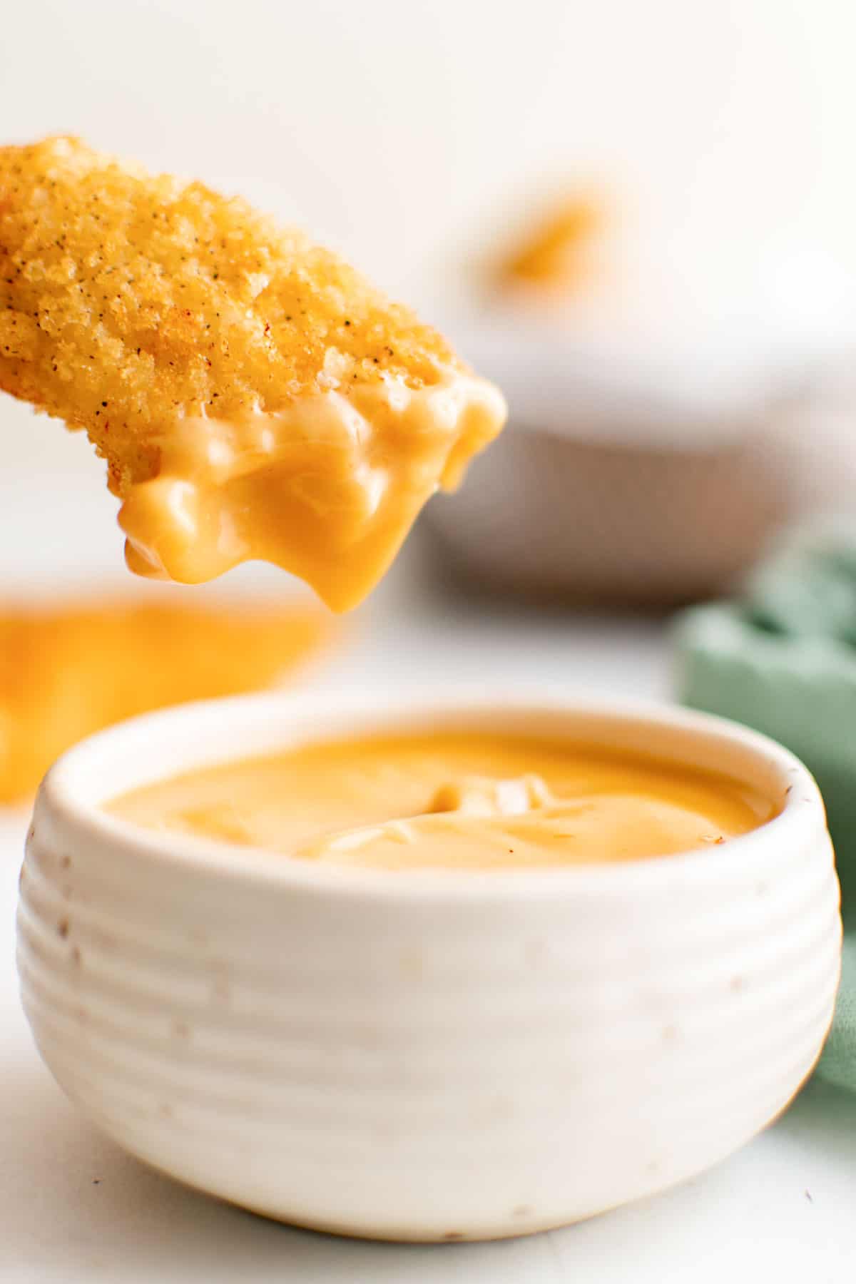 close up view of one of the buttermilk chicken tenders being dipped into sauce
