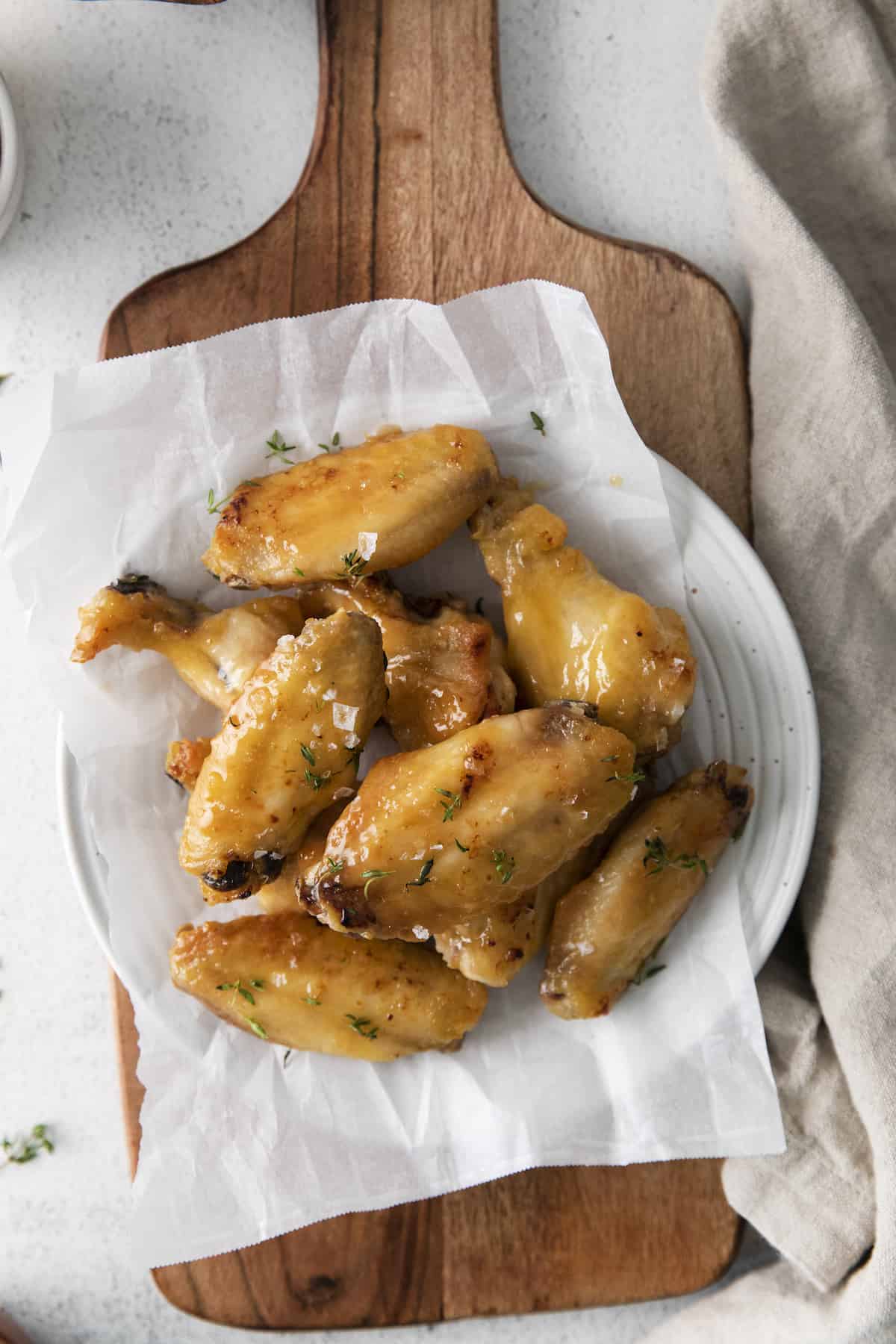 top down view of a plate of oven baked chicken wings on a wooden cutting board