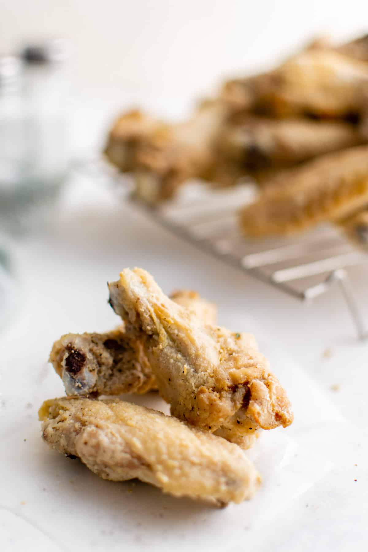 cooked chicken wings on a wire rack with 3 pieces in front