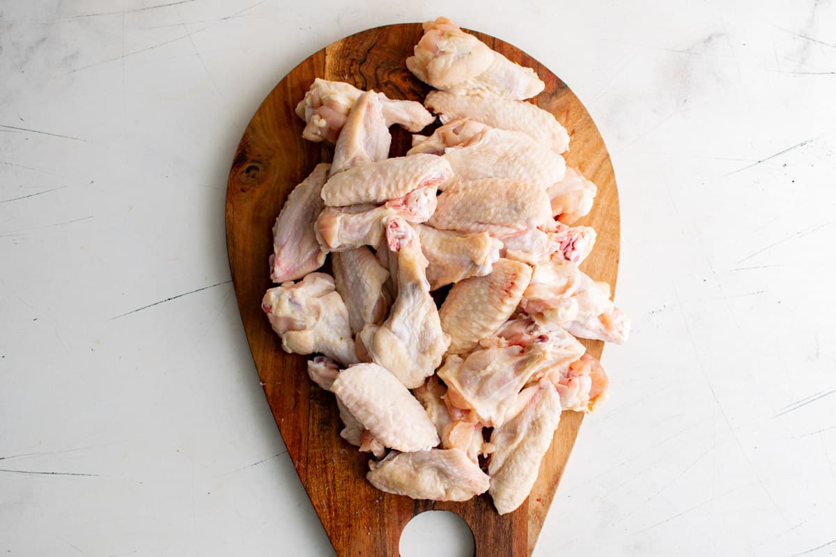 a cutting board holding a pile of uncooked chicken wings for the how many wings in a pound guide