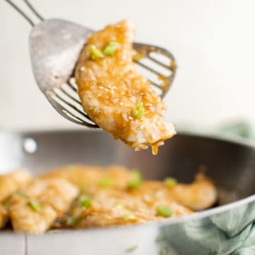 one honey garlic chicken tender on a spatula being removed from a pan