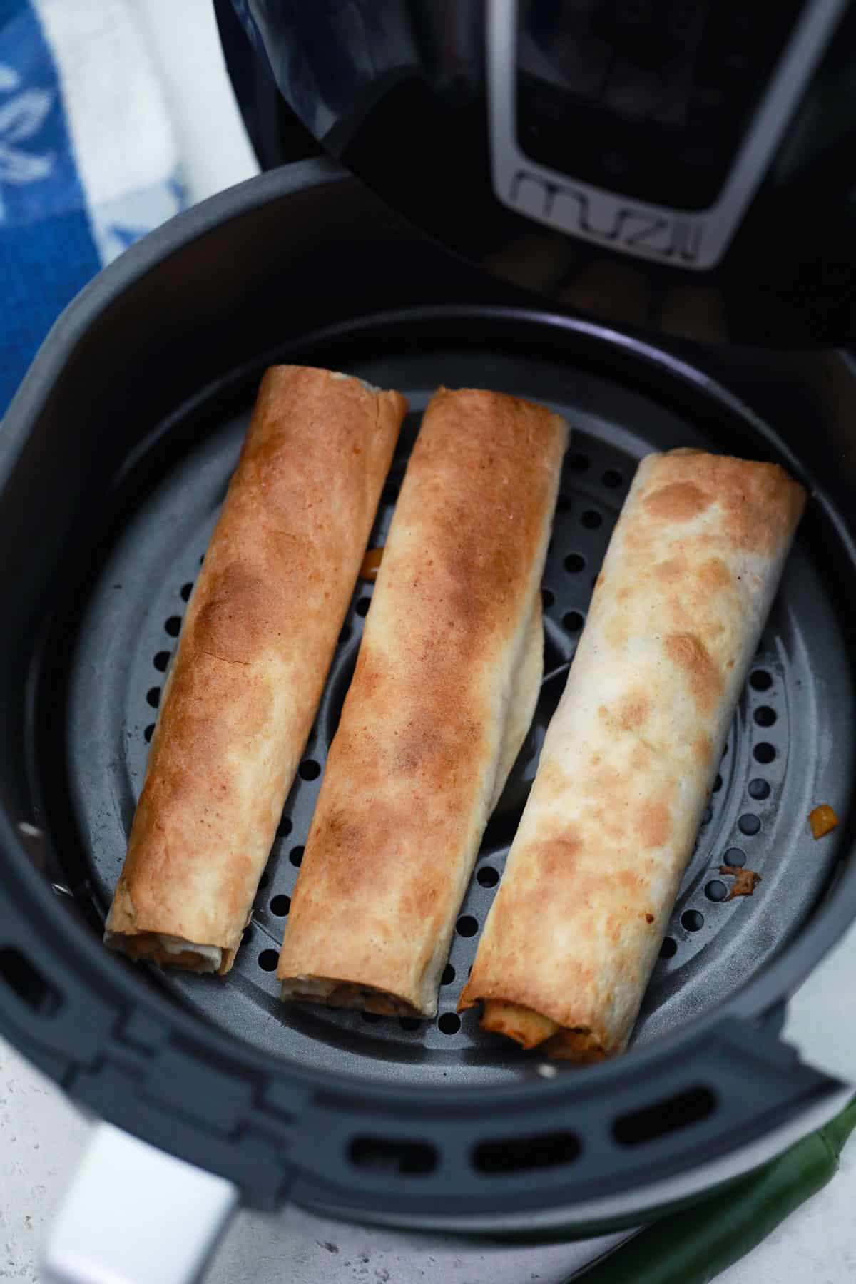 3 air fryer chicken taquitos in an air fryer basket