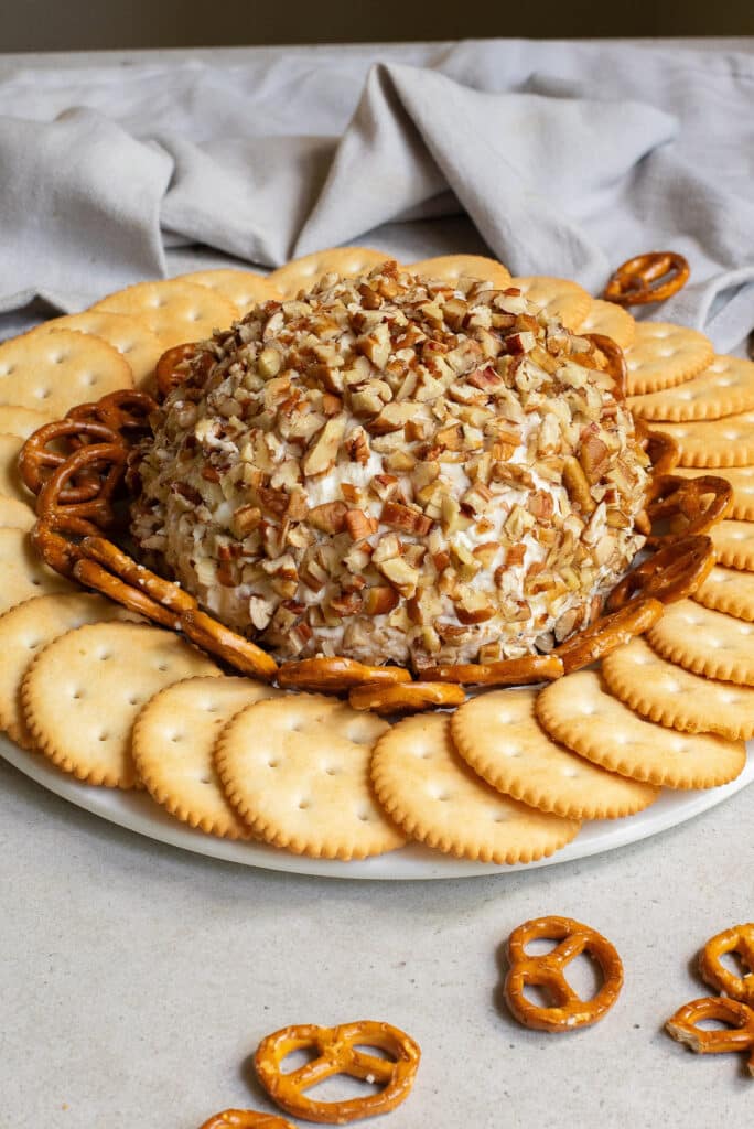 the finished chicken ranch cheese ball on a platter with pretzels and crackers