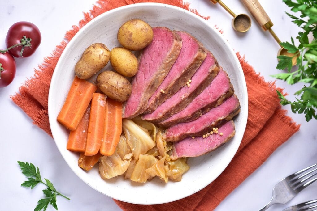 a plate of sliced corn beef, cabbage, carrots, and potatoes.