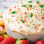 Sugar cookie dip for Christmas in a white bowl with dippers around it.