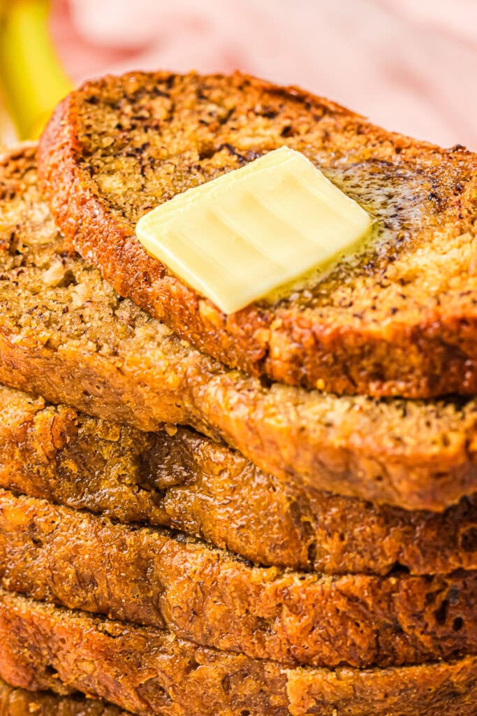 Close-up of a warm slice of Bread Machine Banana Bread topped with a melting pat of butter.