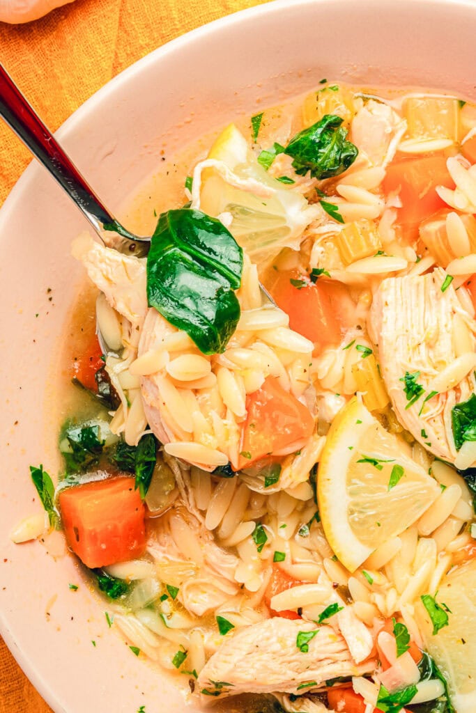 Lemon chicken orzo soup with shredded chicken, orzo pasta, carrots, celery, and spinach in a light lemon broth.